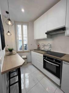 a kitchen with white cabinets and a black stove top oven at Cosy Studio *Vieux-Port* in Marseille