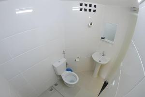 a white bathroom with a toilet and a sink at VA Apart Hotel Savassi in Divinópolis