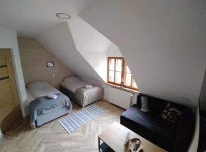 Cette chambre mansardée comprend deux lits et un canapé. dans l'établissement Pokoje Dębowa, à Kazimierz Dolny