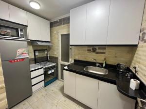 a kitchen with white cabinets and a sink and a refrigerator at Property Sisters, Elite apartment, B11 in Madinaty