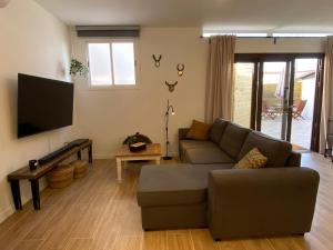 a living room with a couch and a flat screen tv at Private pool, parking, BBQ in the South of GC in Las Palmas de Gran Canaria