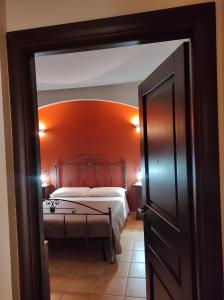 a bedroom with a bed with an orange wall at Le Residenze di Niso in Syracuse