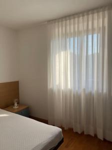 1 dormitorio con cama y cortina blanca en Villa Linfano Isabel, en Nago-Torbole