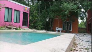a pink house with a swimming pool in front of a house at Casas Teoli Casita Rosa in Valladolid