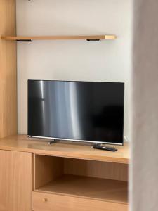 TV de pantalla plana en la parte superior de una estantería de madera en Villa Linfano Isabel, en Nago-Torbole
