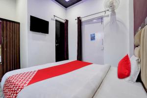 Schlafzimmer mit einem roten und weißen Bett und einem TV in der Unterkunft OYO Flagship Ss Hotel in Kaliānpur