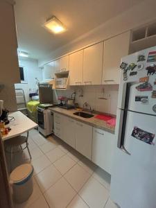 una cucina con armadi bianchi, lavandino e frigorifero di Apartamento ITAIGARA a Salvador