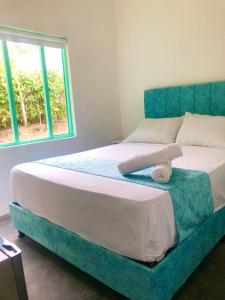 a bedroom with a bed with a blue headboard and a window at Hotel Pallara Campestre in Ricaurte