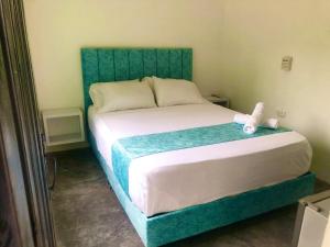 a bed with a green headboard in a room at Hotel Pallara Campestre in Ricaurte