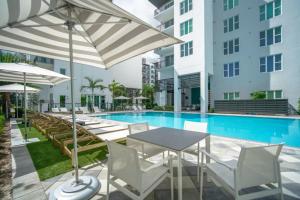 a pool with tables and chairs and umbrellas at Sejur Fort Lauderdale in Fort Lauderdale