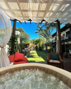 a hot tub in a backyard with a white umbrella at Studios Malakoopa - Praia do Rosa in Praia do Rosa