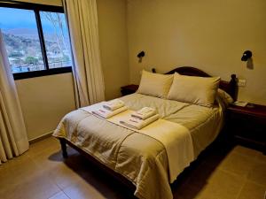 タフィ・デル・バジェにあるHostería La Angosturaのベッドルーム1室(ベッド1台、タオル2枚付)