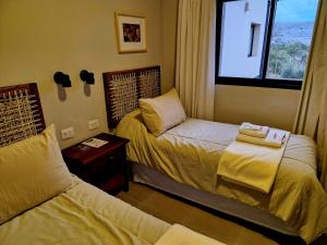 a hotel room with two beds and a window at Hostería La Angostura in Tafí del Valle