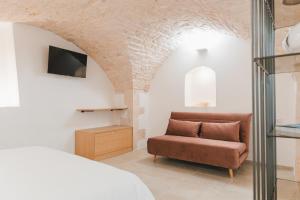 ein Schlafzimmer mit einem Sofa und einem TV an der Wand in der Unterkunft Dimore Bianche lImmacolata in Putignano