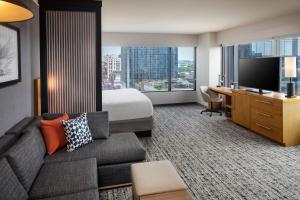 a hotel room with a couch and a bed and a television at Hyatt Place Nashville Downtown in Nashville