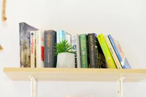 eine Reihe von Büchern auf einem Regal mit einer Topfpflanze in der Unterkunft Spitakia in Chalki