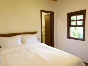 een slaapkamer met een groot wit bed en een raam bij Casa do Aconchego in Gonçalves