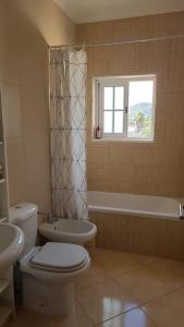uma casa de banho com um WC, um lavatório e uma janela em Stela ' s Guest House em Loulé