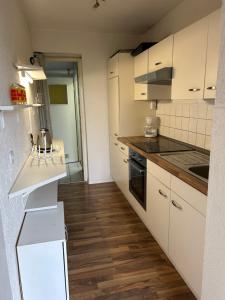 a kitchen with white cabinets and a wooden floor at Am Fuldaufer in Kassel