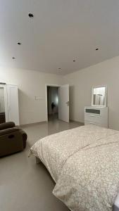 ein weißes Schlafzimmer mit einem Bett und einem Stuhl in der Unterkunft شقة بغرفة نوم وصالة in Unaizah