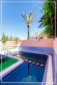 uma piscina com uma palmeira ao lado de um edifício em Fabuleuse Villa Marrakchi em Marrakech