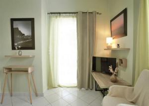 salon z biurkiem, telewizorem i oknem w obiekcie The Green House With Υard w Pireusie