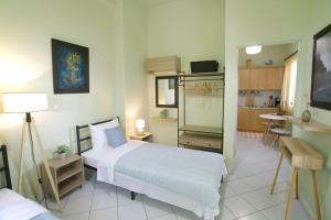 a bedroom with a large white bed and a kitchen at The Green House With Υard in Piraeus