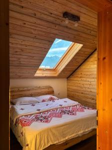 Cama en habitación de madera con ventana en La Văru, en Cârţişoara
