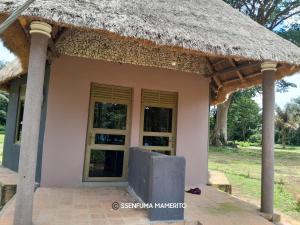 a small house with a thatched roof at Pelican Resort Beach in Kalangala
