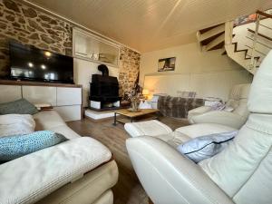 ein Wohnzimmer mit weißen Möbeln und einer Steinmauer in der Unterkunft Le Repos des Rias, maison au cœur de la ville in Quimperlé