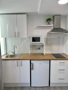 a kitchen with white cabinets and a counter with a microwave at Verdial 1 Atico in Cala del Moral
