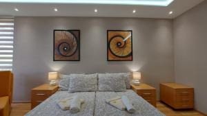 a bedroom with a bed with two lamps and two pictures at Apartman Melodija in Kula