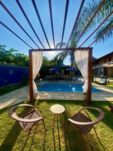 un patio con 2 sillas, una mesa y una piscina en Pousada Lua Cheia, en Búzios