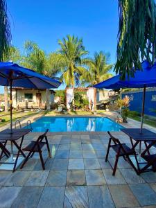 a pool with two picnic tables and umbrellas at Pousada Lua Cheia in Búzios