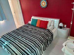 a bed with colorful pillows in a red room at Pousada e Restaurante Mar dos Sonhos in Paripueira