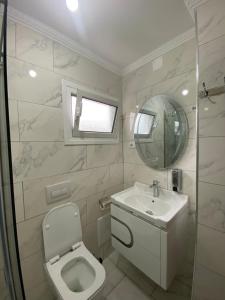 a bathroom with a toilet and a sink and a mirror at Rent Rooms Sakolli in Berat