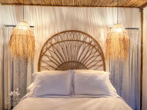 a bed with white pillows and two chandeliers at Habitación luxury Loto Mendihuaca tayrona in Santa Marta
