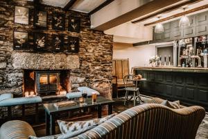 The Hare & Hounds Inn في Bowland Bridge: غرفة معيشة بها موقد وحائط حجري