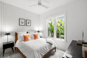 a bedroom with a white bed with orange pillows and a window at NEW! The Humidor - 2 Epic, Luxury Ybor Townhomes, Steps to 7th Ave in Tampa