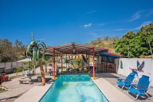 - une piscine avec 2 chaises bleues et un pavillon dans l'établissement Casa, 3 dormitorios, piscina, rancho, cocina, minibar, pingpong, 9 personas, à Capulín