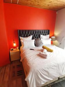 1 dormitorio con pared roja y cama blanca en Neo & Ruks Guest house Parow, en Ciudad del Cabo