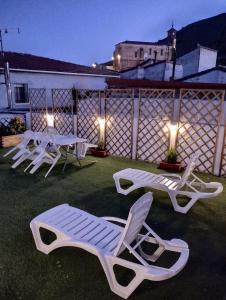 three lounge chairs and tables on a patio at night at Casa Rural "La Muela de Alarilla" 