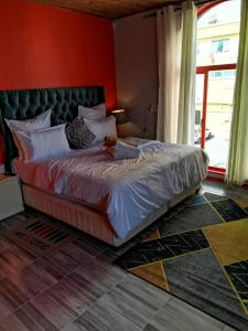 Cama grande en habitación con pared roja en Neo & Ruks Bellville Guesthouse, en Ciudad del Cabo
