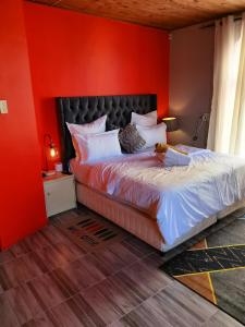 1 dormitorio con 1 cama con pared roja en Neo & Ruks Bellville Guesthouse, en Ciudad del Cabo