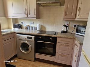 a kitchen with a stove and a washer and dryer at LanEnd House in Whiston