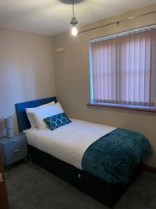 a bedroom with a bed with a blue headboard and a window at LanEnd House in Whiston
