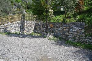 a stone retaining wall next to a fence at Camera di Molly in Leivi