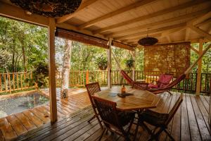 une terrasse en bois avec une table et des chaises. dans l'établissement Au Jardin Des Colibris Ecolodge&Spa, à Deshaies