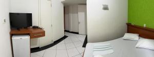 um quarto com uma cama e uma secretária com uma televisão em Hotel 15 de Julho em Foz do Iguaçu
