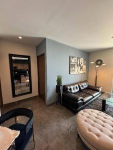 a living room with a leather couch and a table at Lujoso departamento en Monterrey in Monterrey